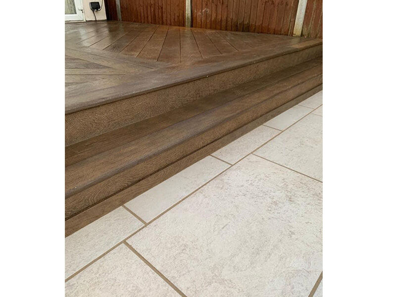 Hardwood decking step meeting a stone patio